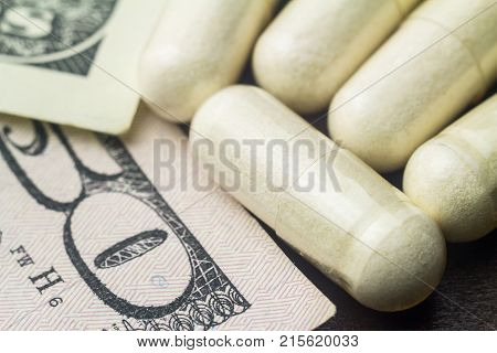 White capsules of glucosamine chondroitin healthy supplement pills on dollar banknote macro image.