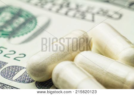 White capsules of glucosamine chondroitin healthy supplement pills on dollar banknote macro image.