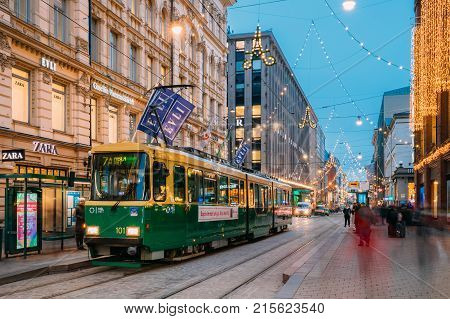 Helsinki, Finland - December 8, 2016: Tram Departs From A Stop On Aleksanterinkatu Street. Night View Of Aleksanterinkatu Street In Kluuvi District In Evening Or Night Illumination.