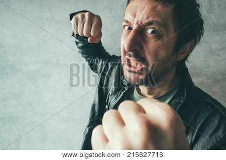Aggressive man punching with fist during the fight from victim's point of view. Violence and crime concept.
