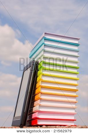 Pile de livres colorés et de lecteur de livre électronique à l'extérieur