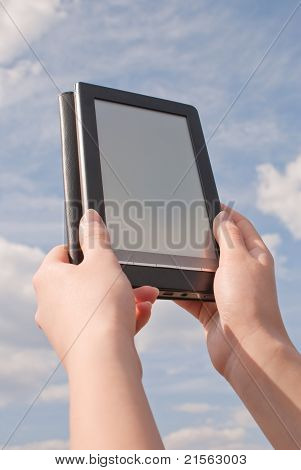Ręce trzymać czytnika książek elektronicznych przeciw błękitne niebo