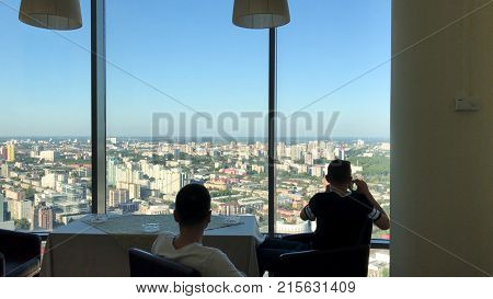 Two mans having lunch at modern restaurant with panoramic window and magnificent city view. friend enjoying each others company while having festive dinner in restaurant with panoramic windows 4K