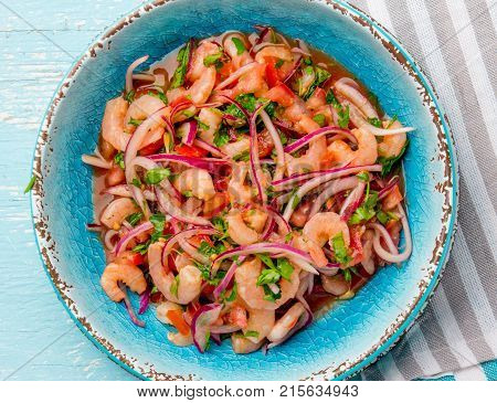 Ecuadorian shrimps ceviche sebiche with tomatoes in blue bowl, wooden blue background. Traditional ecuadorian colombian or mexican dish