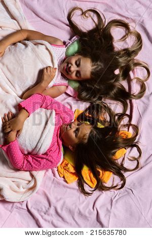 Pajama Party Concept. Girls Lie On Pink Bed Sheets
