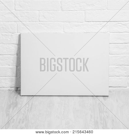 Mockup poster. White blank canvas leaning against a brick wall.