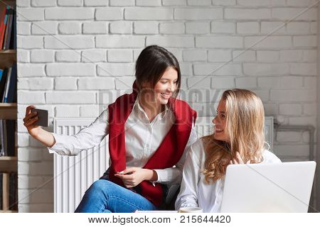 Beautiful young female college friends having fun while studying together at the campus cafe selfies chatting joyfully technology lifestyle leisure communication living urban university educational.