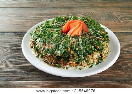 Shot of a pancakes stack sliced and decorated with greens and tomato on top served on the wooden table at the restaurant eating food delicious menu recipe cusine cooking.