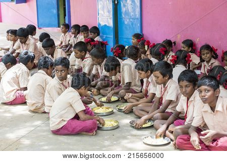 PONDICHERY PUDUCHERY INDIA - SEPTEMBER 04 2017. Unidentified boys girls children sit on the floor with their plate of rice and egg at the lunch time in the outdoor canteen of the school.