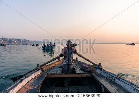 VARANASI INDIA - MARCH 15 2016: Front picture of indian oarsman at the boat at the sunrise in Ganges River in Varanasi India.