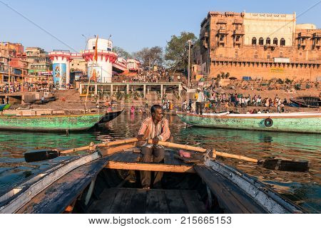 VARANASI INDIA - MARCH 15 2016: Horizontal picture of indian oarsman at the boat in front of Dashashwamedh Ghat inGanges River in Varanasi India.
