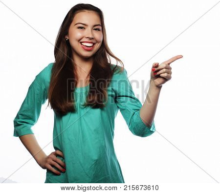 Young smiling woman points a hand with positive facial expressio