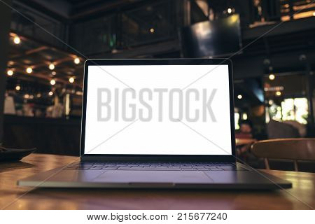 Mockup image of laptop with blank white screen on wooden table in modern loft cafe