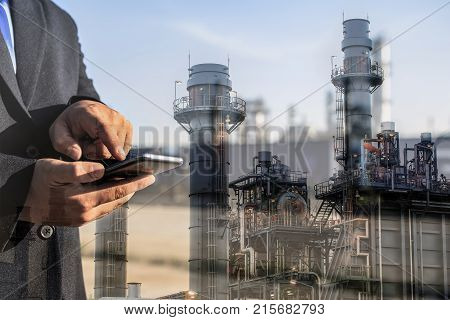 Double exposure of businessman checking oil refinery industry plant by smart phone in the night as Energy and Technology concept