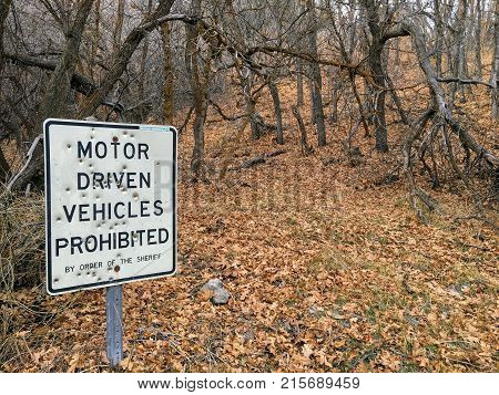 Motor Driven Vehicles Prohibited by order of the Sheriff sign with bullet holes, in forest trail on the Yellow Fork and Rose Canyon Trails in Oquirrh Mountains on the Wasatch Front in Salt Lake County Utah USA.