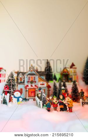 kid gospel choir singing and reads bible in the middle of Christmas village. Winter fairytale miniature scenery