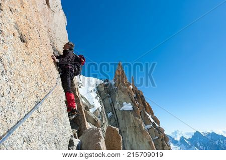 Climbing in Chamonix. Climber on the stone wall of Aiguille du Midi in Mont Blanc, France. Large copy-space on the right. Concepts: determination, concentration, effort, strength, team work.