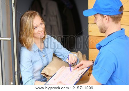 Smiling delivery man in blue uniform delivering parcel box to recipient - courier service concept. Smiling delivery man in blue uniform