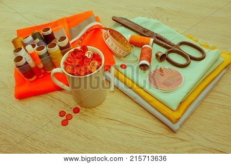 Sewing still life: colorful cloth. scissors and sewing kit includes threads of different colors thimble and other sewing accessories on wooden table. tools for sewing for hobby