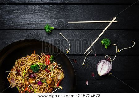 Udon Stir Fry Noodles With Chicken And Vegetables In Wok Pan On Black Wooden Background With Chopsti