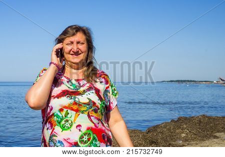 A woman taiking by phone on a beach of a sea