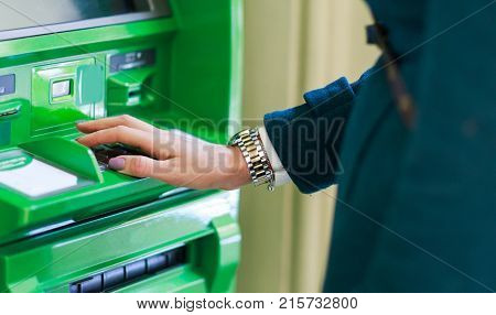 Image of woman in coat at green cash machine in room