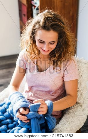 Small business of a young woman. Young woman hand-knitting a wollen blanket.