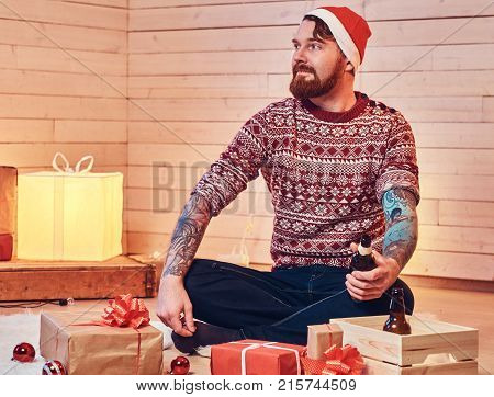 Redhead bearded male in Santa hat in a room with Christmas decoration.