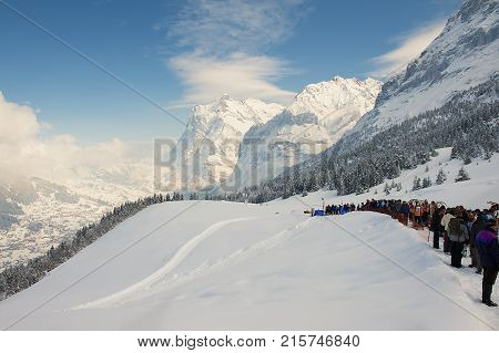 GRINDELWALD, SWITZERLAND - MARCH 07, 2009: Unidentified people enjoy mountain view waiting in line to take part in the annual Horn-Sledge Race from Alpiglen to Grund in Grindelwald, Switzerland.