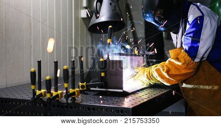 Worker welds at the factory working in metal industry