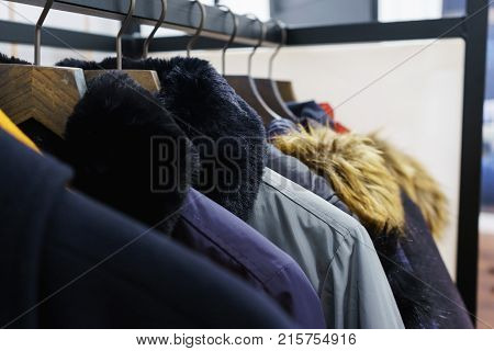 Modern outerwear in a shop on a hanger. Jackets, parks and warm outerwear of different colors and denim for youth. Outerwear of different styles on the hanger in the showroom. Soft focus.