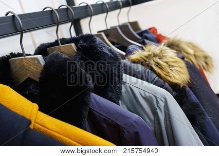 Modern outerwear in a shop on a hanger. Jackets, parks and warm outerwear of different colors and denim for youth. Outerwear of different styles on the hanger in the showroom. Soft focus.