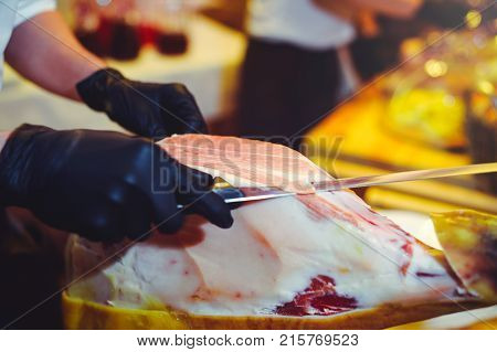 Sliced Dried Chamon Prosciutto. A Man Cuts A Jamon, A Warm Toned Image. Selective Focus Point