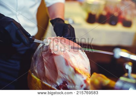 Sliced Dried Chamon Prosciutto. A Man Cuts A Jamon, A Warm Toned Image. Selective Focus Point