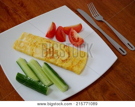 Classic omelet with tomatoes and cucumbers on the white plate. Fresh breakfast.