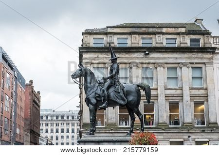 Statue of Duke of Wellington riding a horse wearing a black traffic cone on his head. In front of Gallery of Modern Art Royal Exchange Square Glasgow Scotland.