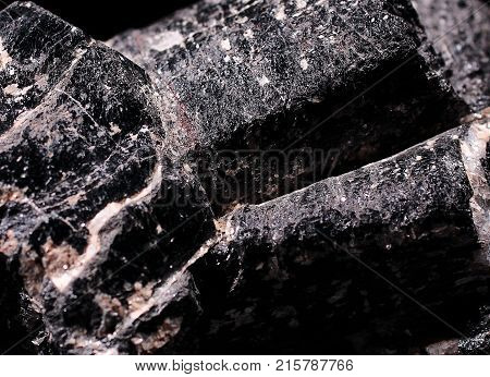 Closeup photograph of tourmaline stone on black background. Natural phenomenon. Black, gray and white.
