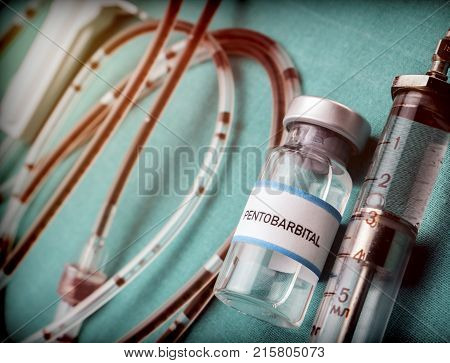 Rubber drip irrigation system with traces of blood along with vial of sodium thiopental, conceptual image