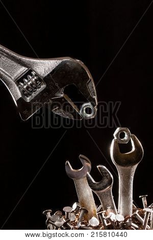 Conception of an adjustable wrench feeding baby wrenches in a nest of nails