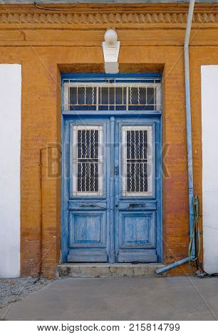 Old blue wooden doors in Cyprian village. Framed by orange painted wall.