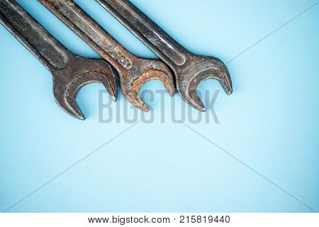 Three old rusty spanners on blue background. Workshop equipment. Quality metal tools. Vintage wrench close up. Top view.