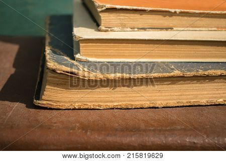 Closeup of several vintage books horizontally placed on the leather background. Stack of old books in hardcover. Back to school.