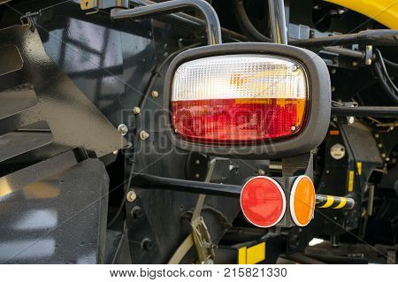 Close up of tractor headlight and cataphot selective focus. Tractor red and orange lights against the background of the details of the car body. Design and technology