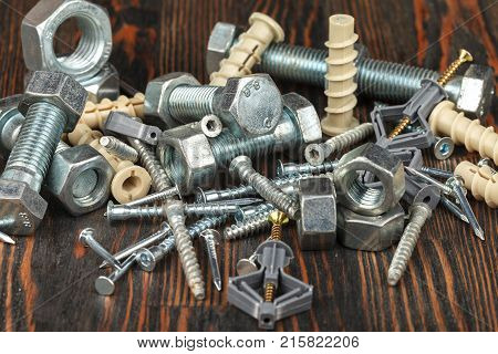 Metal bolts nails screws and plastic dowels for mounting and fixing. Close-up. Studio lighting.