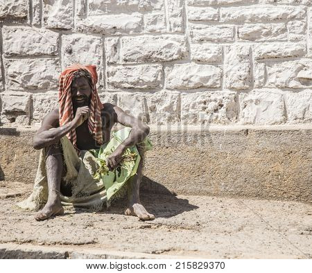 HARAR, ETHIOPIA-MARCH 31, 2017: An unidentified man sits in rags with a handfull of khat, a stimulant drug.