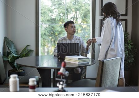 Female scientist in a lab coat researching with her male coed med school student in a campus laboratory. The woman is learning science and technology in medical industry.