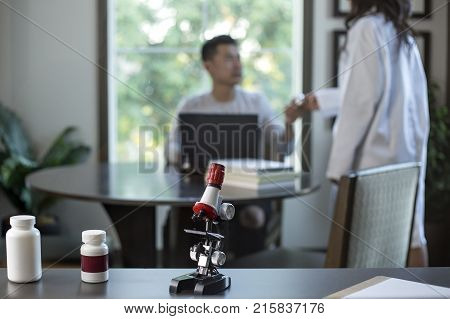 Female scientist in a lab coat researching with her male coed med school student in a campus laboratory. The woman is learning science and technology in medical industry.