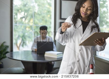 Female scientist in a lab coat researching with her male coed med school student in a campus laboratory. The woman is learning science and technology in medical industry.