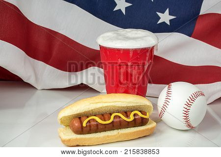 overflowing beer in red cup and baseball with hot dog and American flag background
