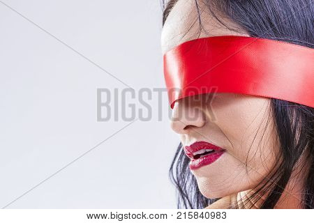 Closeup Portrait of Caucasian Brunette Woman Posing with Red Ribbon Blinder on Eyes with Passionate Expression.Horizontal Image Composition